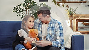 daddy read a book to her daughter at home. kid dream coronavirus stay home concept. daddy is sitting on the couch with