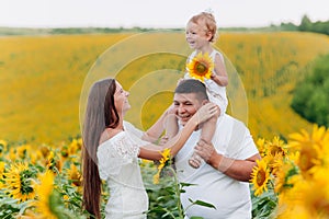 Daddy`s carrying a baby daughter on his shoulders in the field of flowers. The concept of summer holiday. Father`s, mother`s, b