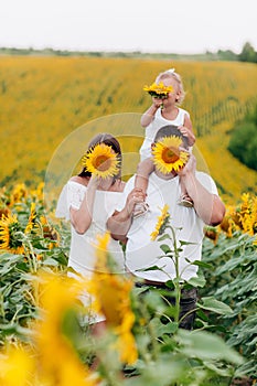 Daddy`s carrying a baby daughter on his shoulders in the field of flowers. The concept of summer holiday. Father`s, mother`s, b