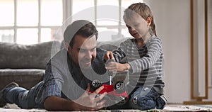 Daddy teaching cute kid son playing toy car on floor