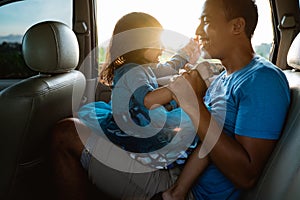 Daddy tickling her little girl in the car