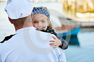 Daddys coming home. Rearview shot of a father in a navy uniform hugging his happy little girl.