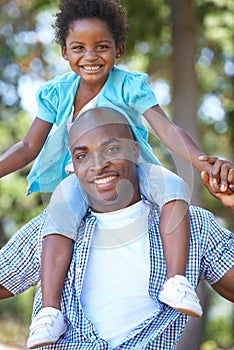 Daddys girl loves nature. Portrait of a father carrying his daughter on his shoulders while enjoying a day outdoors.