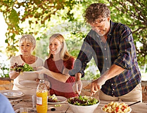 Dads in charge of dishing up. A view of a family preparing to eat lunch together outdoors.