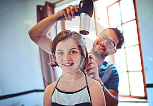 Dads my personal and favourite stylist. a father blowdrying his little daughters hair at home.