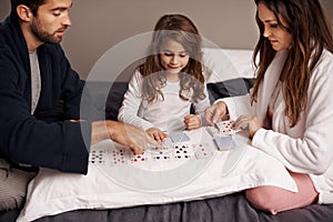 Dads teaching her a new game. a young family playing cards together at home.