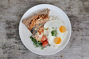 Daing Na Bangus with sunny egg and rice with tomato with salad served in dish isolated on wooden background top view of breakfast
