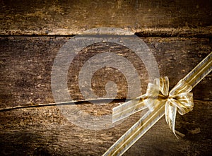 Dainty gold bow on a rustic wood background