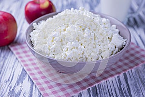 dairy product cottage cheese in a plate with a glass of milk and apples