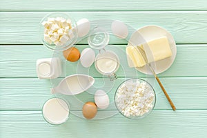 Dairy products from farm with milk, eggs, cottage, butter, yougurt on mint green wooden background top view