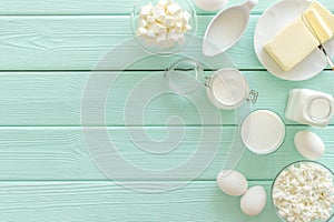 Dairy products from farm with milk, eggs, cottage, butter, yougurt on mint green wooden background top view mockup
