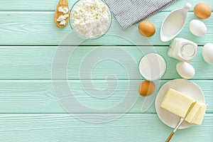 Dairy products from farm with milk, eggs, cottage, butter, yougurt on mint green wooden background top view mockup