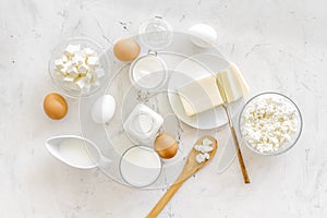 Dairy products from farm with milk, eggs, cottage, butter, yougurt on white marble background top view