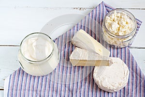 Dairy products. Sour milk cheese, sour cream, camembert and brie with checkered napkin on light blue wooden table