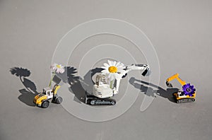 Daisy flowers on the arrows of three toy construction vehicles - excavators