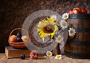 Daisy flowers in a vase with fresh fruits in a vicker basket