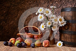 Daisy flowers in a vase with fresh fruits in a vicker basket