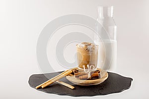 DalgonÃÂ° coffee in a glass glass, a bottle of milk with breadsticks, cinnamon