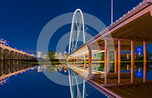 Dallas night lights reflect in water under bridge