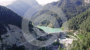 Dam, Emerald lake aerial view in wooded valley. Dam, Emerald lake captured by drone, mountain scenery. Dam, Emerald lake