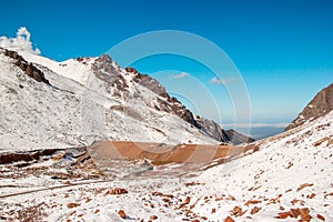 Dam between mountain slopes. Snow mountains and blue skies