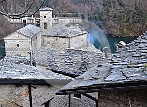 Dam and stone roofs and a chimney that smokes in the village of Isola Santa on the shore of the homonymous lake, magic in the hear