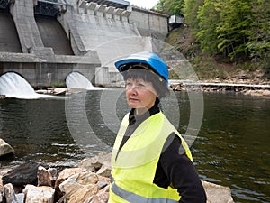 Dam and turbines of a hydroelectric power station with falling water flows and woman in helmet