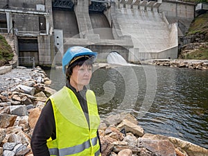 Dam and turbines of a hydroelectric power station with falling water flows and woman in helmet