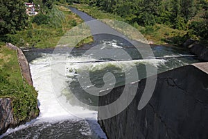 Dam wall and overflow of Iskar Dam. Water flowing over a dam wall. Mist rising above the Iskar dam wall. Cascade from a hydroelect