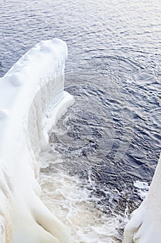 Dam at winter flowing water and ice