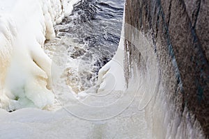 Dam at winter flowing water and ice
