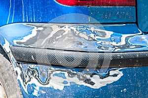 Damage on blue scratched car bumper with damaged and peeled paint in crash accident or parking lot