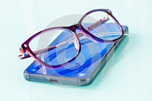 Damage to eyesight by staring at smartphone screen for too long, Health concept, Glasses lying on phone emitting blue light