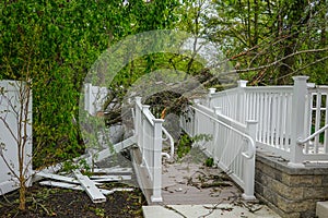 Damage to a white metal fence and guard rail of a deck and ramp from a tree that fell during a storm