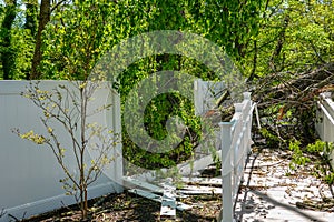 Damage to a white metal fence and guard rail of a deck and ramp from a tree that fell during a storm