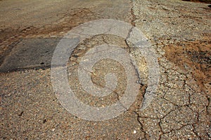 Damaged asphalt road with potholes. Bad road. Bad asphalt, Broken automobile road, cracks, holes, potholes in asphalt