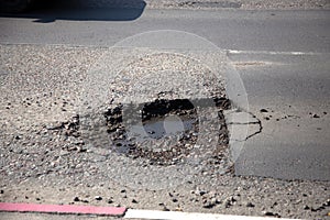 Damaged asphalt road with potholes. Bad road. Bad asphalt, Broken road, cracks, holes, potholes in the asphalt