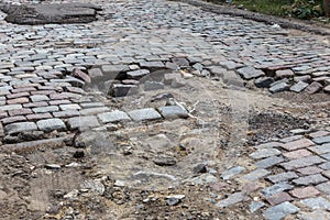 Damaged asphalt road with potholes, caused by freeze-thaw cycles in winter. Bad road. Broken pavements sidewalks on sidewalk.