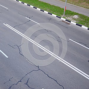 Damaged bad asphalt road with potholes. Patch repair of asphalt