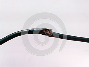 Damaged black electric cord on wooden floor background. Dangerous broken electrical cable