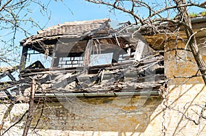 Damaged and broken collapsed roof of the abandoned house after fire from grenade bomb, with tiles and blue sky background