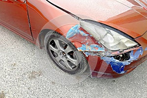 Damaged in a car crash in front of an orange car parked