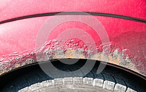 Damaged corroded red car with scratched paint and rust close up