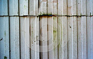Damaged corrugated fence texture with green spots