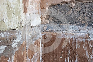 Damaged damp plaster exposing brick in a bathroom.