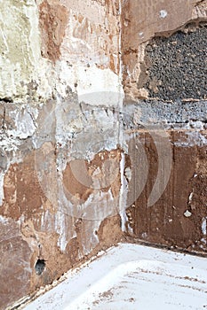 Damaged damp plaster exposing brick in a bathroom.