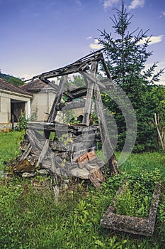 Damaged and destroyed wooden well in abandoned village.