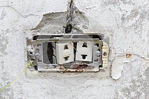 Damaged electric socket in old cement wall, rusty socket