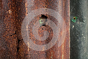 Damaged galvanized iron sheet wall on old warehouse. Detail view of old rusty corrugated metal sheet