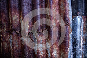 Damaged galvanized iron sheet wall on old warehouse. Detail view of old rusty corrugated metal sheet